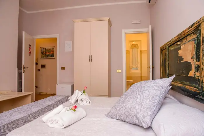Camera con bagno privato: il letto matrimoniale con la testiera antica e gli asciugamani piegati