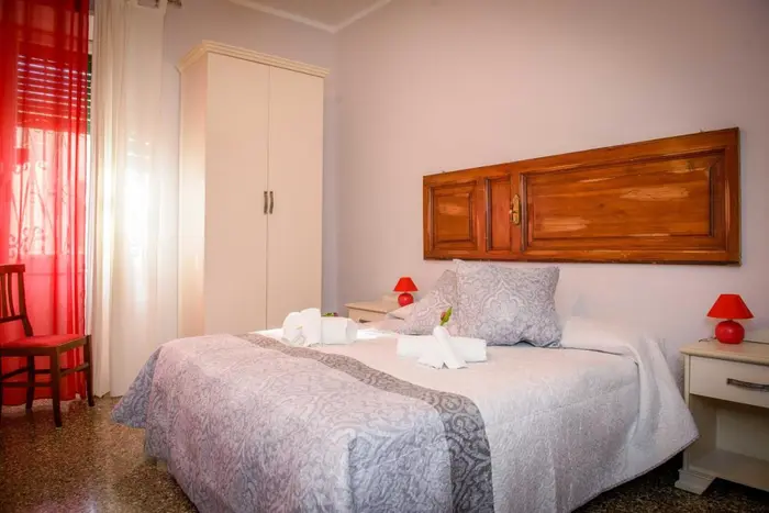Camera con bagno esterno: il letto matrimoniale con la testiera in legno e le tende rosse