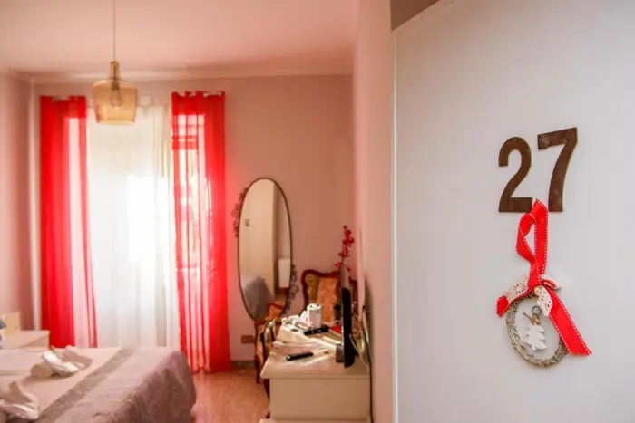 La camera 27, con le tende rosse, lo specchio e il letto matrimoniale
