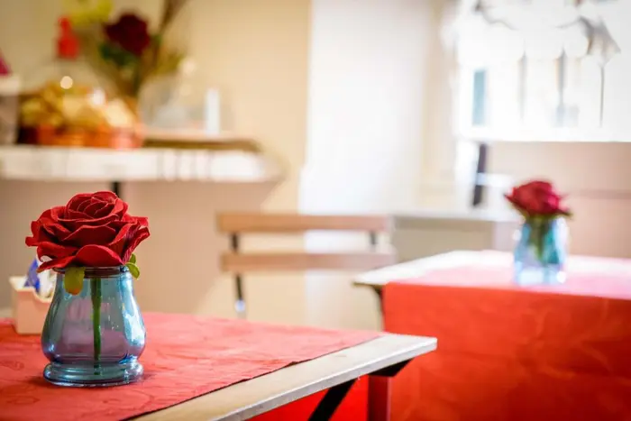 I tavoli della colazione con le tovaglie rosse e una rosa in un vaso di vetro