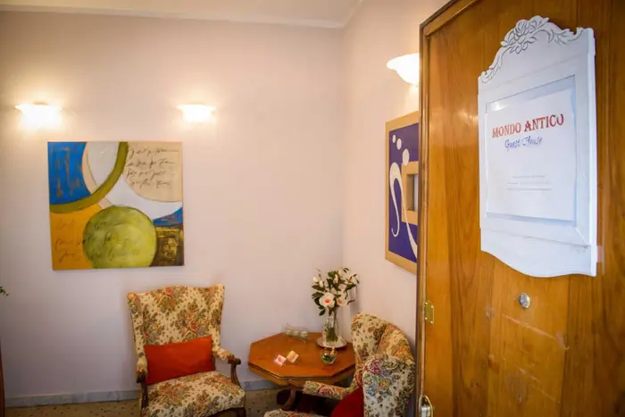 La sala comune con le poltrone, un tavolino e l'insegna di Mondo Antico